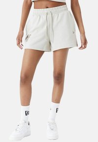 Hellgraue Baumwollmischung-Shorts mit elastischem Bund, Kordelzug und gesticktem Logo-Detail am Saum. Getragen mit weißen Socken und Turnschuhen.