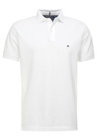 Polo shirt blanc à manches courtes en coton, doté d'une patte de boutonnage à deux boutons et d'un petit logo brodé sur la poitrine gauche.