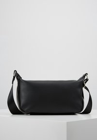 Borsa a tracolla in pelle nera con forma rettangolare, texture liscia e ferrature argentate. Dotata di una tracolla lunga regolabile e dettaglio con cerniera.