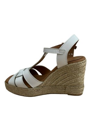 Sandalia de cuña de cuero blanco con diseño de tiras entrecruzadas, tacón envuelto en yute, punta abierta y plantilla de cuero marrón. Suela plana y texturizada.