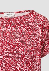 Rode shirt met korte mouwen met een wit geometrisch patroon, ronde halslijn en zachte stoftextuur. Merklabel zichtbaar op de kraag.
