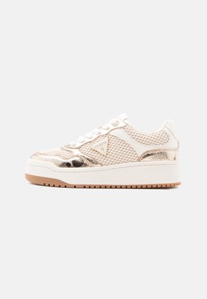 Cream-colored sneaker with mesh panels, metallic rose gold accents, white laces, thick white sole, and Guess logo on side.
