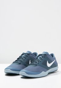 Blue athletic shoes with a mesh upper, featuring a textured design, padded collar, and white Nike swoosh logo on the side.