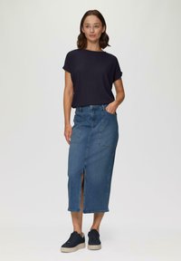 Top azul marino texturizado, falda de mezclilla de cintura alta con abertura frontal y dos bolsillos laterales; modelo combinado con zapatillas oscuras.