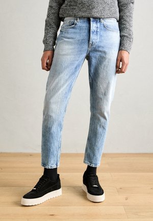 Lichtblauwe denimjeans met een normale pasvorm en een vervaagde textuur. Gecombineerd met zwarte suède sneakers en een grijze gebreide trui.