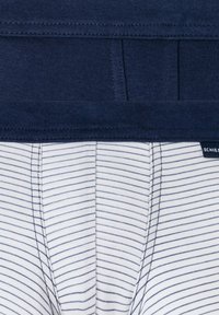 Marineblauer Bund über weißen Boxershorts mit dünnen marineblauen Streifen. Weicher, dehnbarer Stoff mit sichtbaren Nähten und einem Etikett am Bund.
