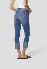 Denim cropped jeans in mediumblauw met geborduurde zoomdetail. Voorzien van vijf zakken en een gebrandmerkt label aan de achterkant.