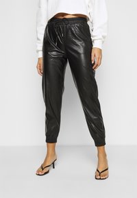 Svarta joggers i konstläder med elastisk midja och vristmanschetter, med en slät yta och snörningsdetalj.