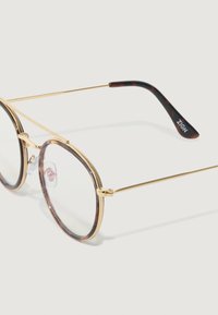 Ronde bril met een doorzichtig montuur, gouden metalen accenten en donkere schildpadarmen. Heldere lenzen en verstelbare neuskussentjes.