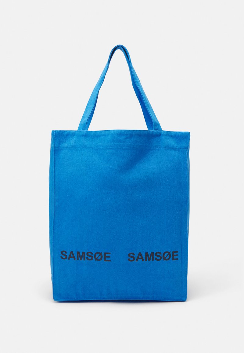 Bolsa de lona azul con dos impresiones de texto en negro "SAMSE" en la parte inferior. Presenta dos asas resistentes y una forma rectangular simple.