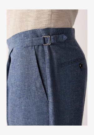 Blue linen trousers with a subtle texture, a silver buckle at the waist, pleated front, and a back pocket detail.