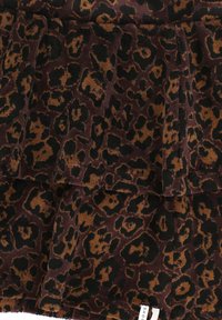 Bruin en zwart luipaardprintstof met een zachte, fluweelachtige textuur, met subtiele plooien en een klein wit kledinglabel.