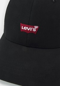 Fekete, hasított anyagból készült sapka, amelyen a piros Levi's logó hímzett a frontpanelen, ívelt karimával és texturált felülettel.