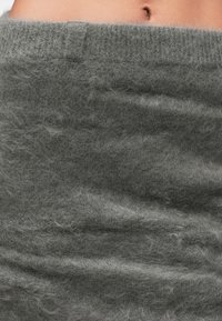 Kratak pogled na meku, puhastu sivo tkaninu omotanu oko struka, s vidljivom kožom i pupkom na gornjoj ivici.