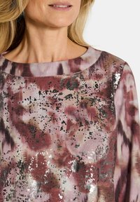 Langemouwen top met een ronde halslijn, gemaakt van een zachte stof met een textuurdesign van roze, bordeauxrood en grijze spetters, inclusief metallic accenten.