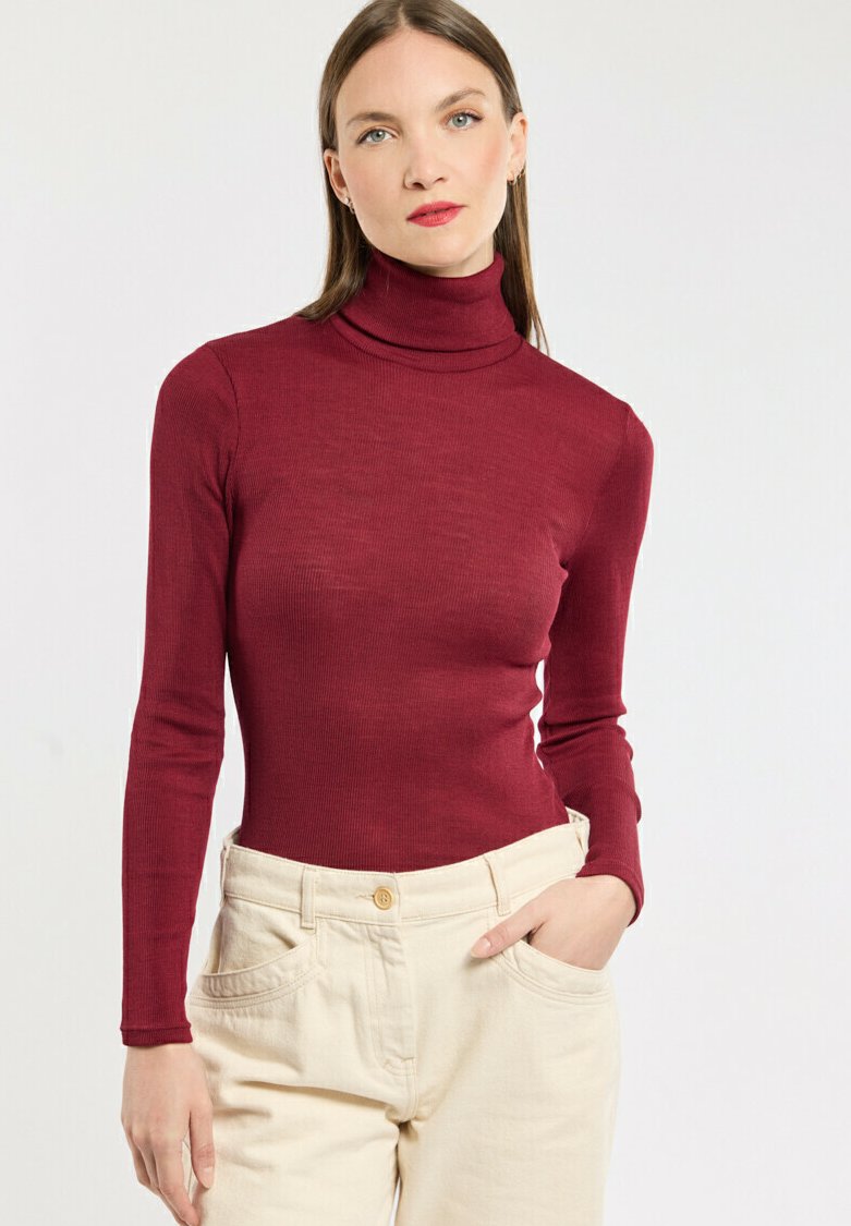 Burgunderfarbene Rollkragenoberteil mit langen Ärmeln, geripptem Textur, kombiniert mit cremefarbenen, hoch taillierten Hosen mit Fronttaschen.