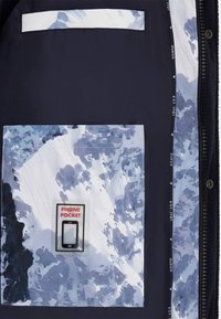Intérieur d'une veste noire présentant une poche pour téléphone à motif bleu et blanc avec une étiquette "POCHE POUR TÉLÉPHONE", entourée de textures de tissu élégantes.