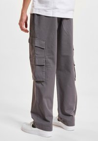 Gray cargo pants featuring multiple side pockets and a relaxed fit, made from lightweight fabric, paired with white sneakers.