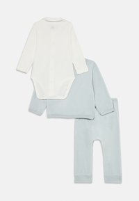 Ensemble pour bébé trois pièces comprenant un body à manches longues crème avec boutons-pression et un pull léger bleu clair assorti ainsi que des pantalons en tissu doux.