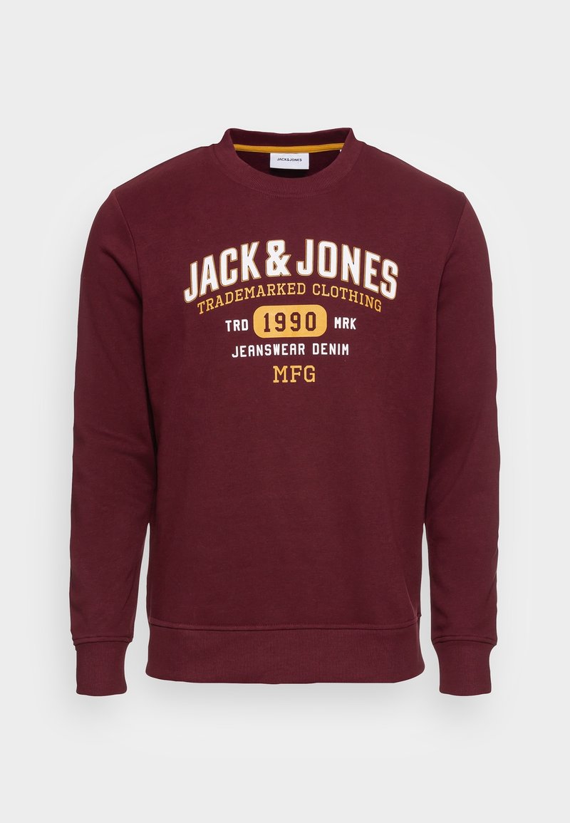Sweat-shirt col rond bordeaux avec les inscriptions "JACK & JONES," "1990," et "JEANSWEAR DENIM MFG" imprimées en jaune et blanc sur la poitrine.