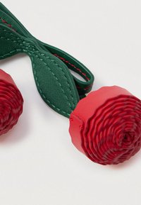 Κόκκινες υφασμάτινες τεχνητές κερασιές με πράσινα ραμμένα δερμάτινα φύλλα σε λευκό φόντο.