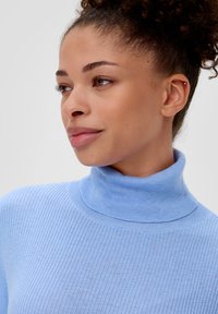 Hellblaue gerippte Rollkragenpullover mit taillierter Passform und strukturierter Oberfläche, der einen hohen Kragen und subtile Nähte aufweist.