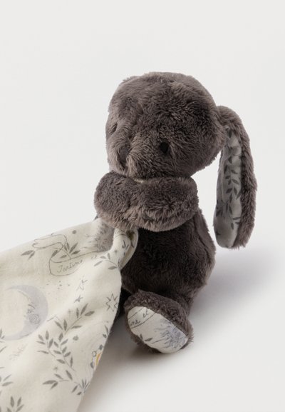 Απαλό γκρι κουνελάκι που κρατάει μια λευκή κουβέρτα με μοτίβα φεγγαριού, αστεριών και φύλλων σε λευκό φόντο.