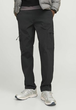 Black cargo pants made of lightweight fabric; features zippered pockets on the sides and a tapered leg design. Paired with silver running shoes.
