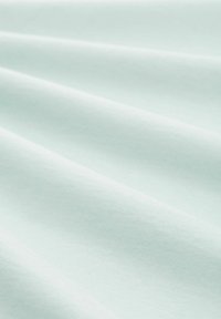 Svetle aquamarínová tkanina s jemnými, hladkými záhyby. Materiál se jeví jako lehký a tkaný, s konzistentní barvou po celém povrchu.