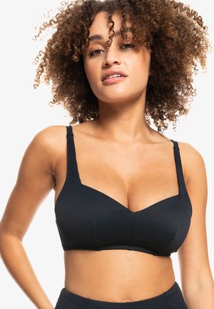 Svart ribbet bralette med underwire-beskyttelse, justerbare stropper og en dyp utringning. Glatt tekstur, uformell design og tettsittende stil.