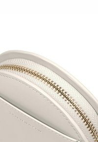 Okrągła biała torba z gładkiej skóry z kontrastowym, teksturowanym zamek błyskawicznym oraz złotym metalowym okuciem.