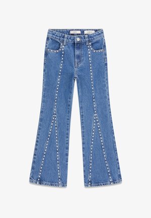 Jean flare bleu ajusté avec des clous argentés le long des coutures avant et des poches, fermeture par bouton et style cinq poches.