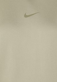 Beige tygbakgrund med en subtil Nike swoosh-logotyp centrerad nära toppen.