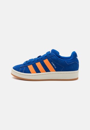 Zapatilla de ante azul con tres rayas naranjas, entresuela blanca, suela de goma, texto "CAMPUS" en el lateral y cuello acolchado.