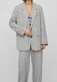 Grå randig kostym med en lång blazer med spetsiga slag, enknappstängning och matchande vida byxor med framveck. 