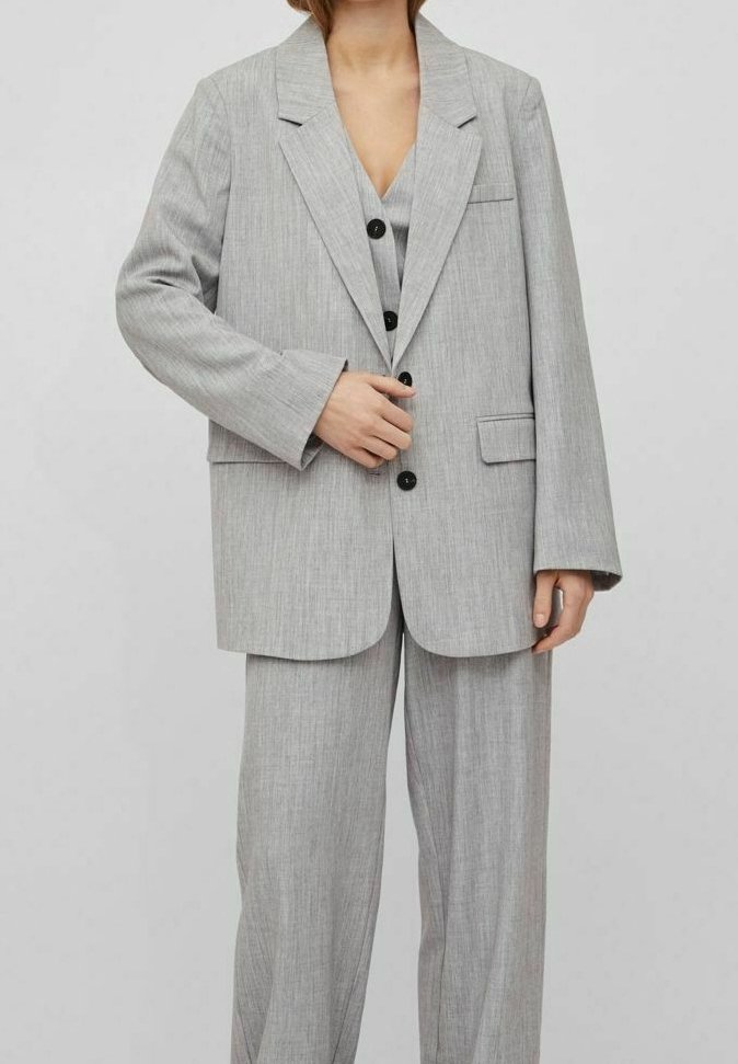 Grå randig kostym med en lång blazer med spetsiga slag, enknappstängning och matchande vida byxor med framveck. 
