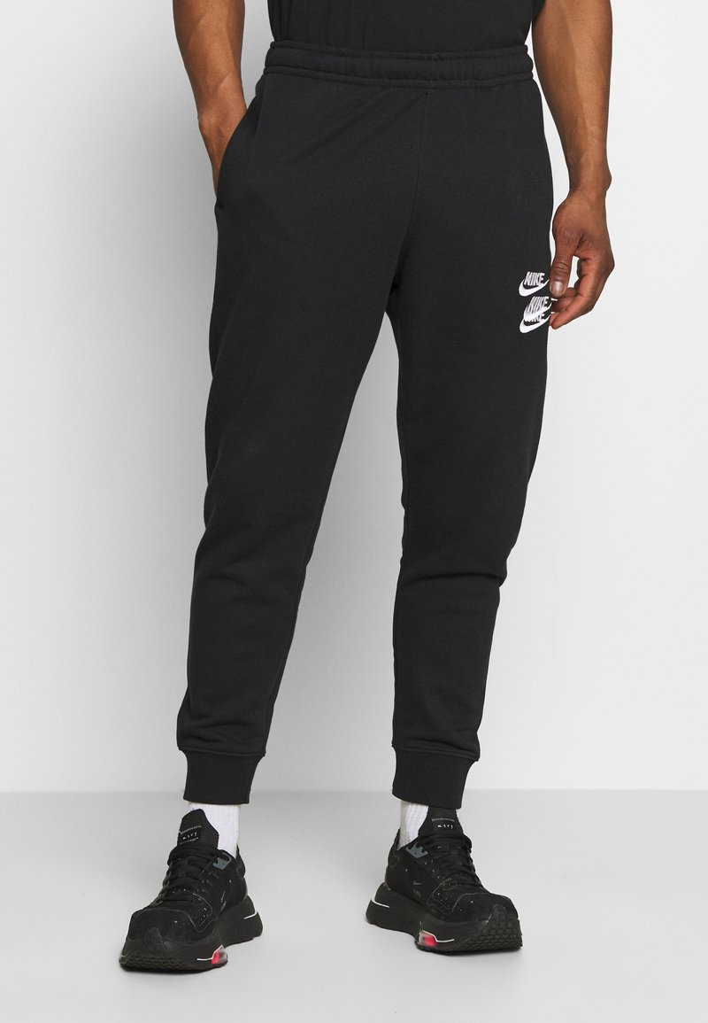 Svarta bomullsjoggers med elastiskt midjeband, sidofickor och vita Nike-logotyper på låret. Slim fit med ribbad fåll vid anklarna.