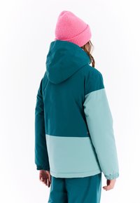 Tücleanfarbene und hellgrüne isolierte Jacke mit Kapuze, elastischen Bündchen und einer rosa gestrickten Mütze. Glatte Textur, modernes Design, keine sichtbaren Logos.