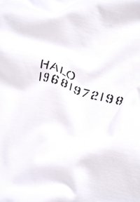 Biała bawełniana tkanina z czarnym nadrukowanym tekstem: "HALO 19681972198" w przesuniętym układzie, prezentująca gładką, miękką fakturę.