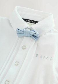 Polo bianca in cotone con tessuto strutturato, papillon azzurro chiaro e bottoni argentati. Logo "BAKER" in azzurro chiaro sul davanti.