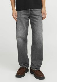 Grå raka jeans i denim med en blekt tvätt, femficksdesign och sömdetaljer. Bärs med bruna skor.