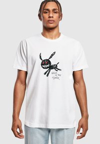 Hvid bomulds t-shirt med en sort tegneseriefigur med røde øjne og teksten "WALK IN THE DARK" i en legesyg, skitse-lignende stil.