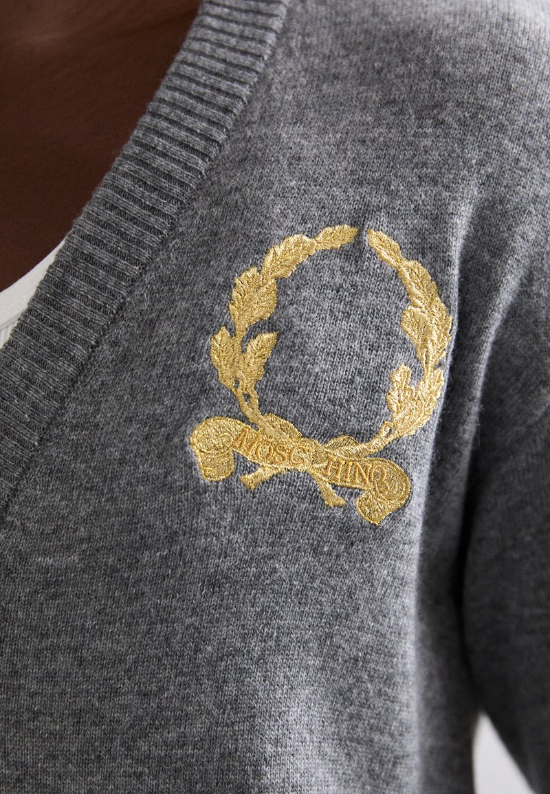 Grau gestrickte Strickjacke mit gerippten Kanten, die ein golden gesticktes Lorbeerkranz- und Banddesign mit "MOSCHINO" zeigt. Weiche Textur.