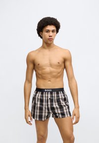 Fekete, barna és krémszínű kockás mintájú boxeralsó. Rugalmas derékrész „BOSS” logóval. Könnyű anyag, bő szabás.