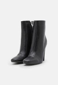 Botines de cuero negro con puntera afilada, tacón alto y cierre de cremallera lateral. Textura suave y diseño elegante para una silueta ajustada.