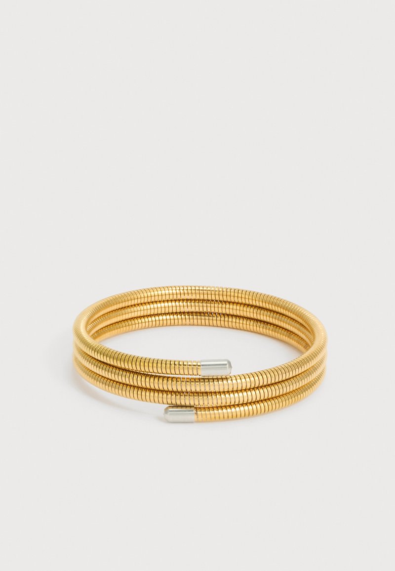 Bracelet flexible enroulé de couleur or avec trois boucles et embouts cylindriques argentés sur fond blanc.