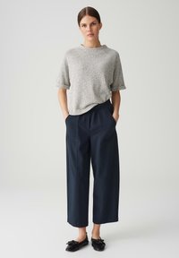 Grijze, gestructureerde top met korte mouwen gecombineerd met marineblauwe, wijde broek met een elastische tailleband. Zwarte ballerina's met strikdetail maken de outfit compleet.