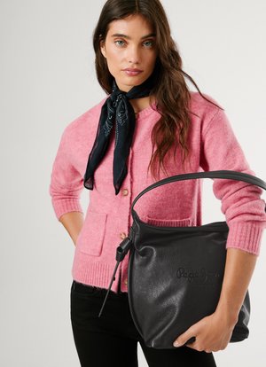 Roze wollen cardigan met knoopsluiting en zakken, gedragen over zwarte broeken. Zwarte leren tas met logo, handvat en ritsopening.