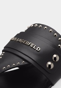 Μαύρο δερμάτινο σανδάλι slide με ασημένιες τελείες και μεταλλικό λογότυπο «KARL LAGERFELD» στο λουρί.
