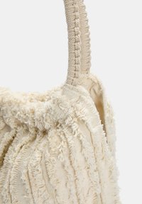 Cream textured fabric bag featuring a braided handle, with a plush, wavy pattern and a soft, fuzzy surface.